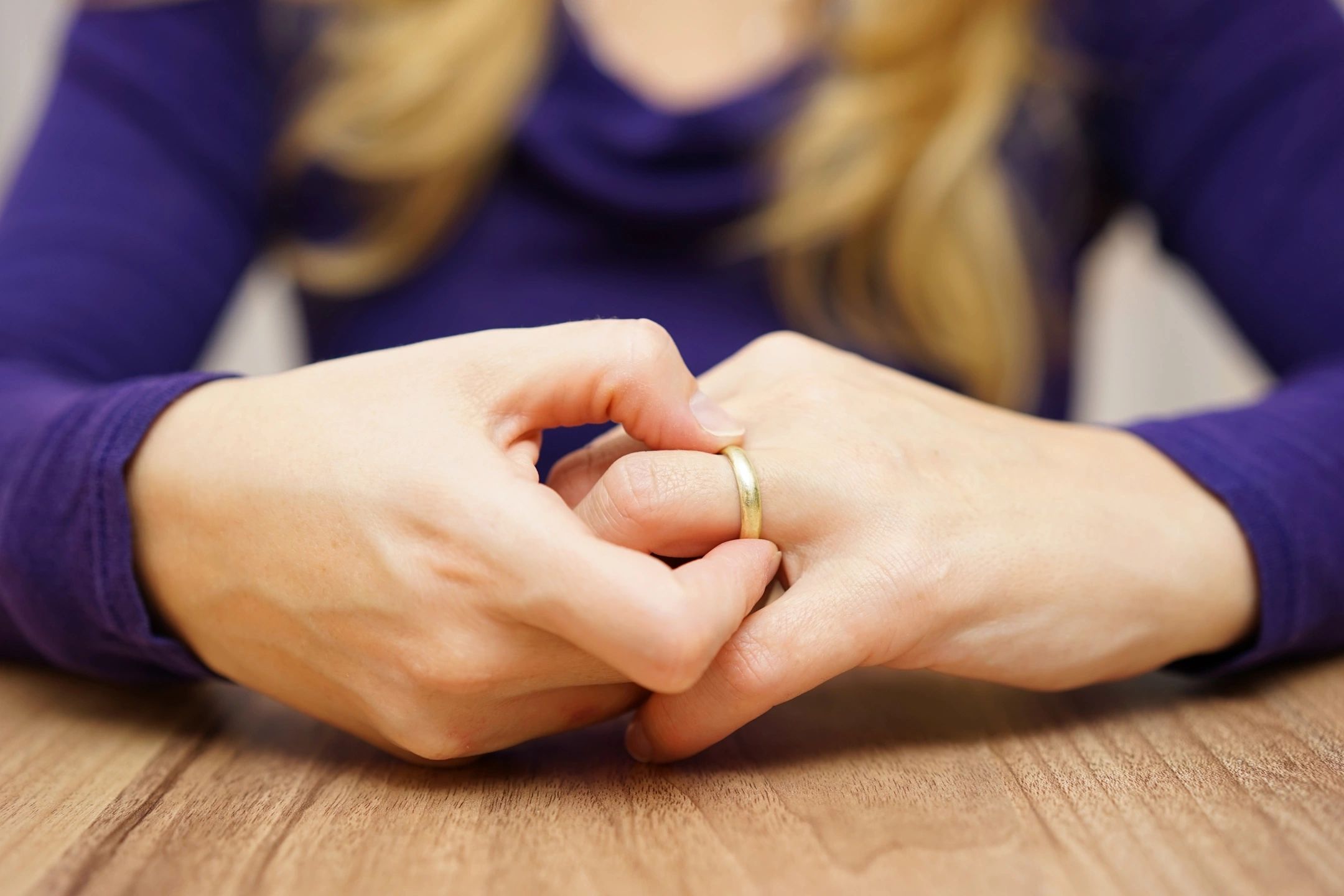 Woman holding her ring while considering divorce after infidelity.